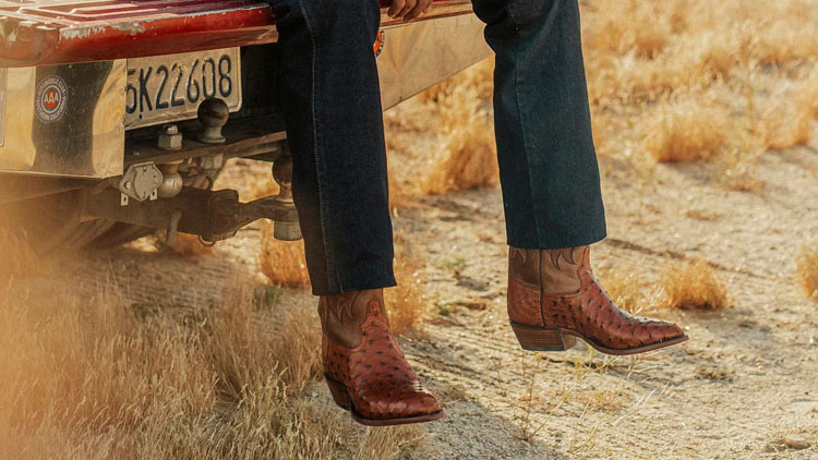 A man wearing a pair of Signature Series boots sitting on a red truck.